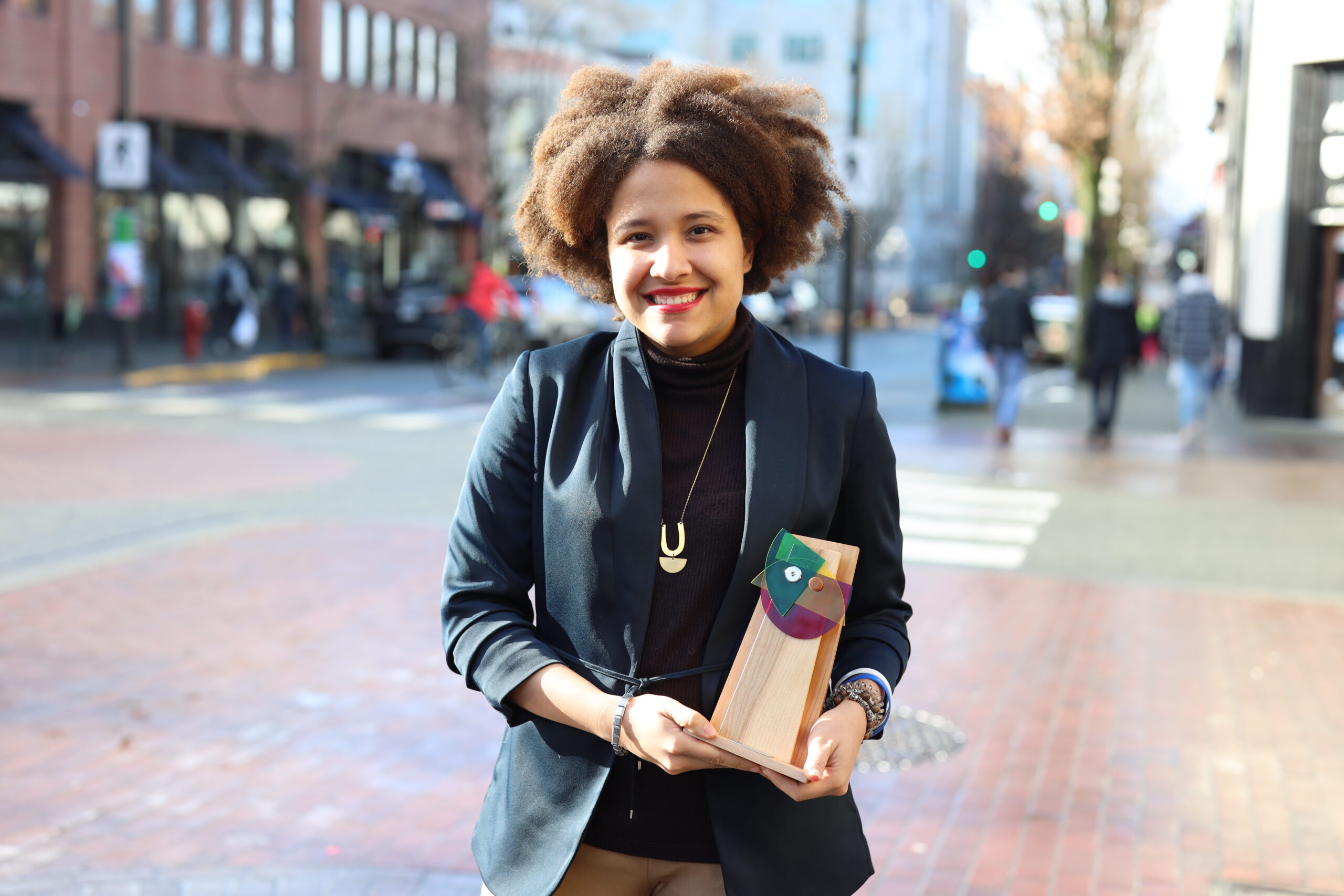 a woman smile while holding an award outside