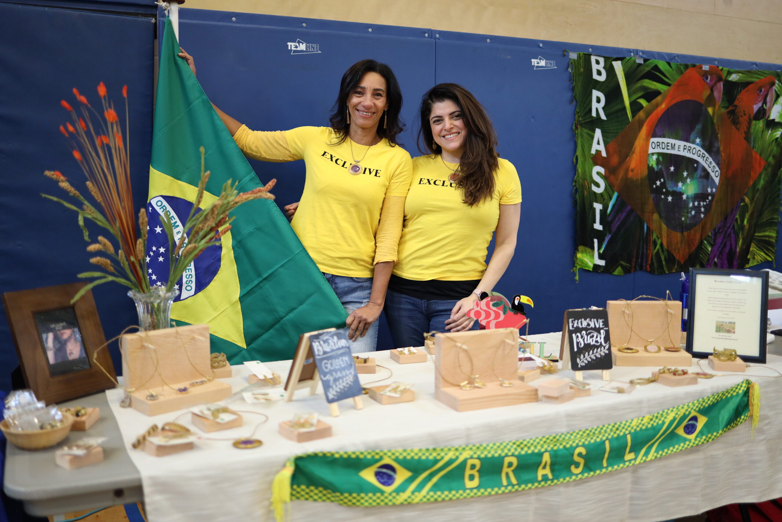 two women pose at table with the Brazilian flag